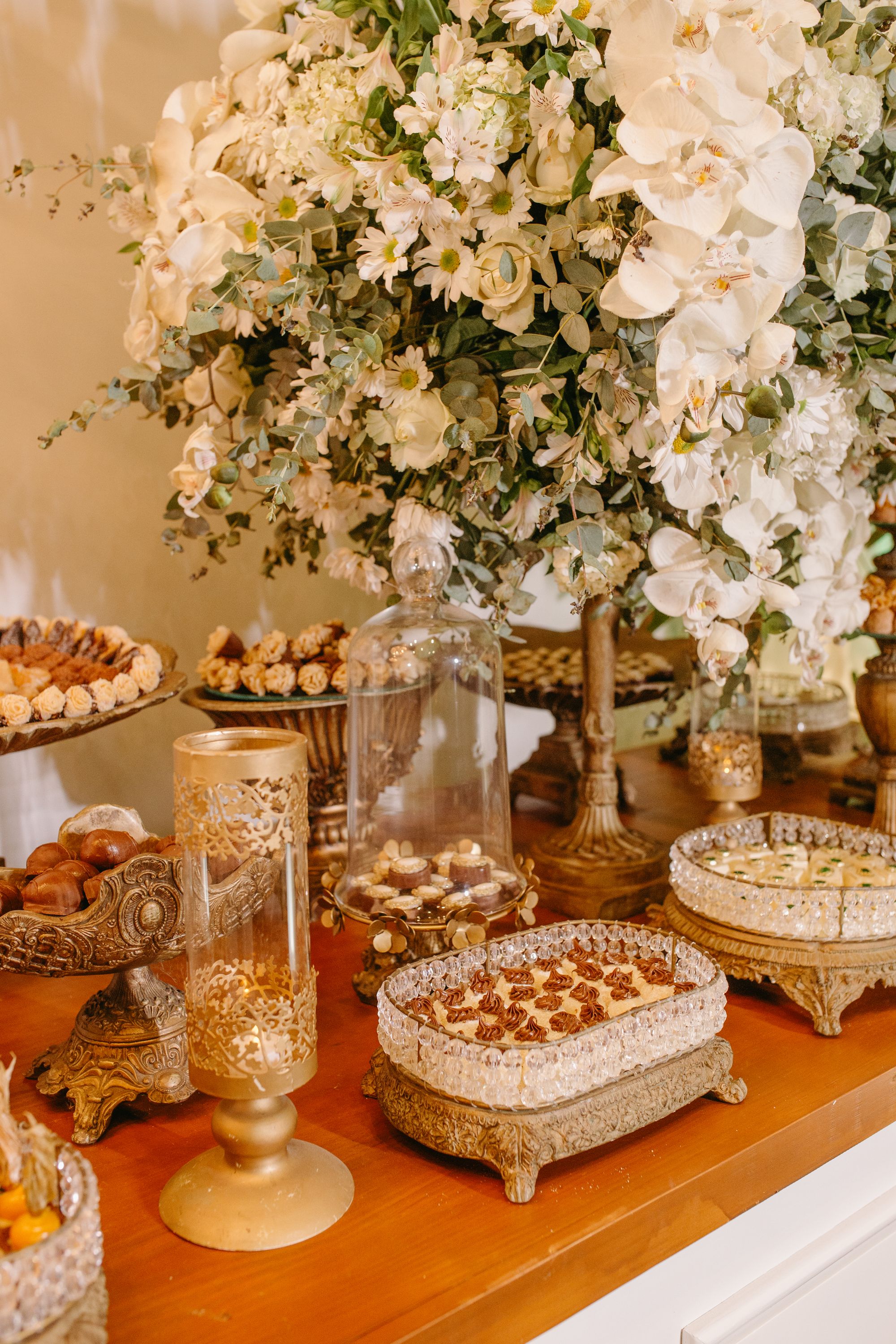 Professional dessert display with white orchids and elegant gold and crystal trays