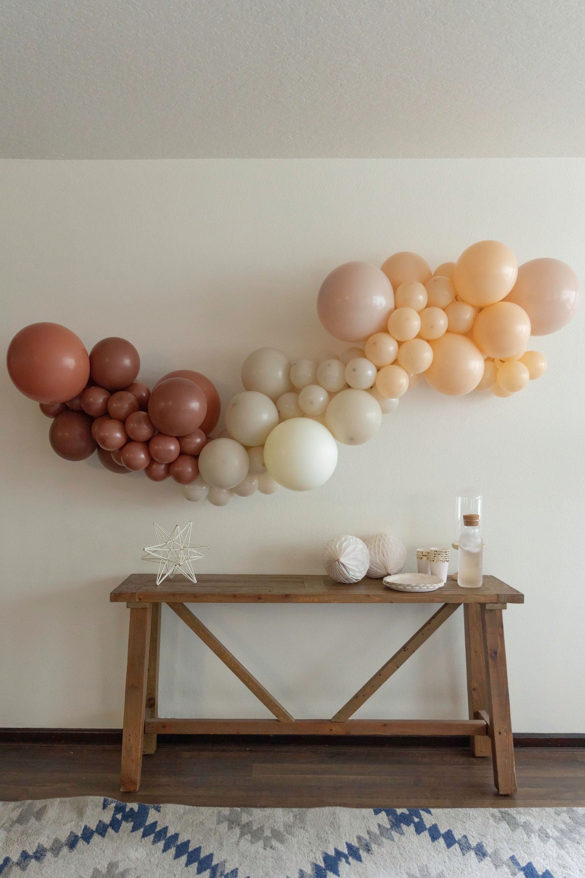 Mocha, caramel, and ivory balloon garland above a welcome table